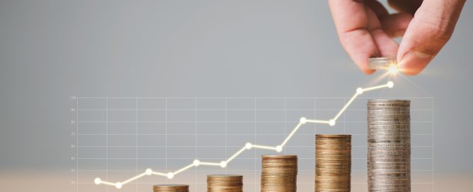 Person stacking coins with a graph going upwards