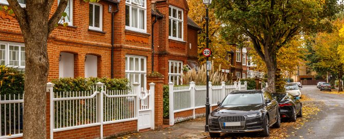 Autumn view of traditional UK houses with trees in fall colours lining a residential street.