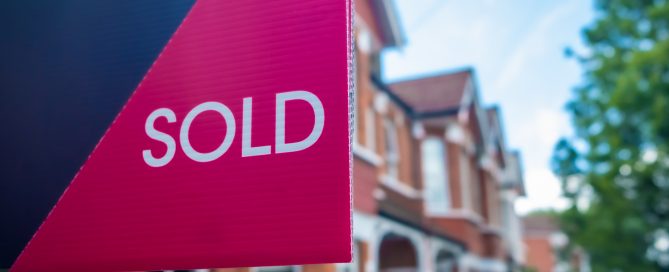 Sold sign in front of a residential brick house indicating a completed property sale