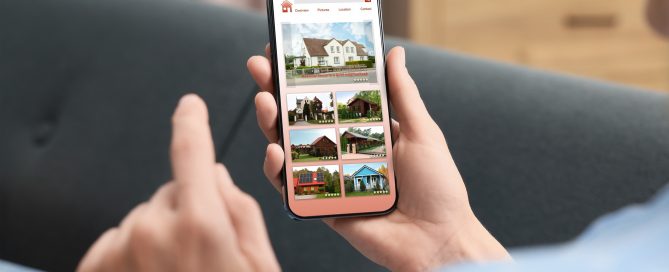 A person sitting on a sofa holds a smartphone displaying a real‑estate app with house listings, photos, and ratings.