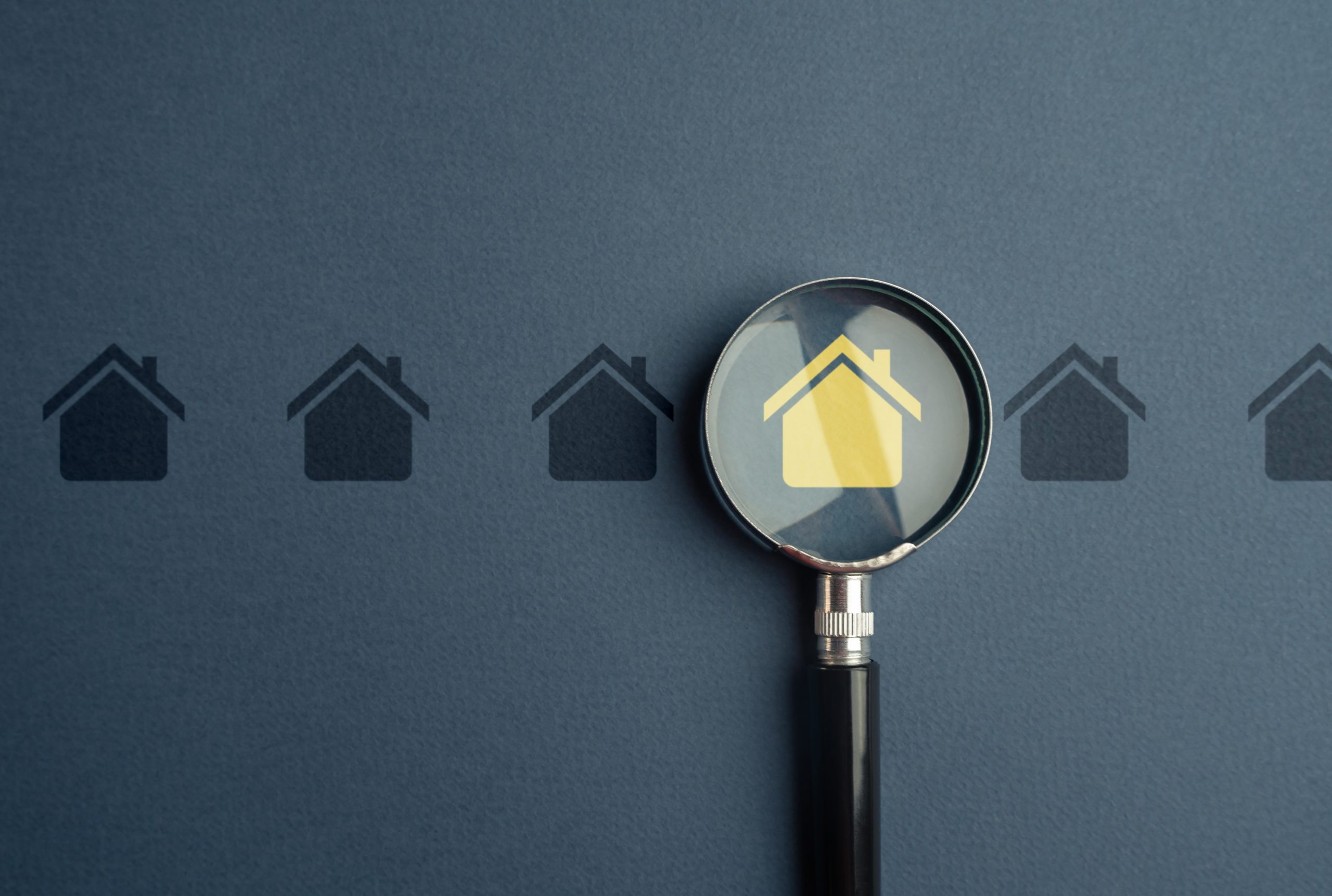 Magnifying glass focusing on a highlighted house icon, symbolising local property search, residential real estate listings, home buying, and property market research.